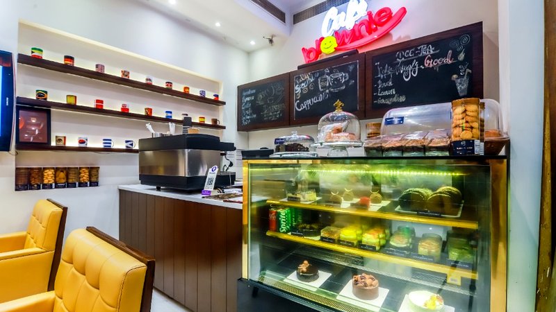 Café Brownie refrigerated pastry display counter with fresh brownies, cakes, espresso coffee machine, and chalkboard menu