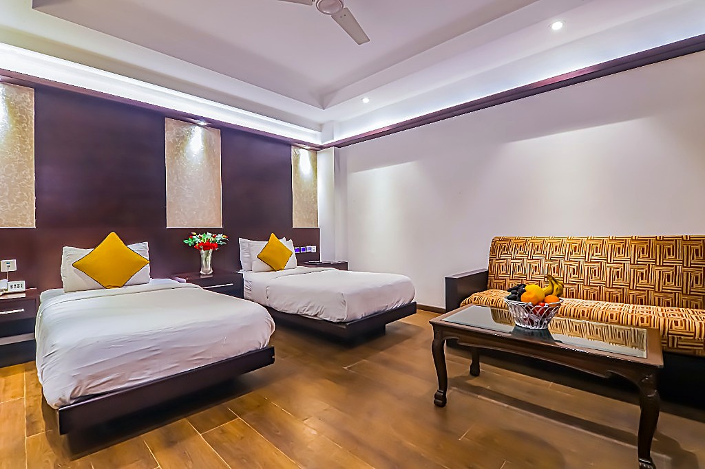 Premier Twin Bed Room with Air-Purifier at Hotel Godwin Deluxe — two plush twin beds, designer sofa lounge, and warm ambient lighting