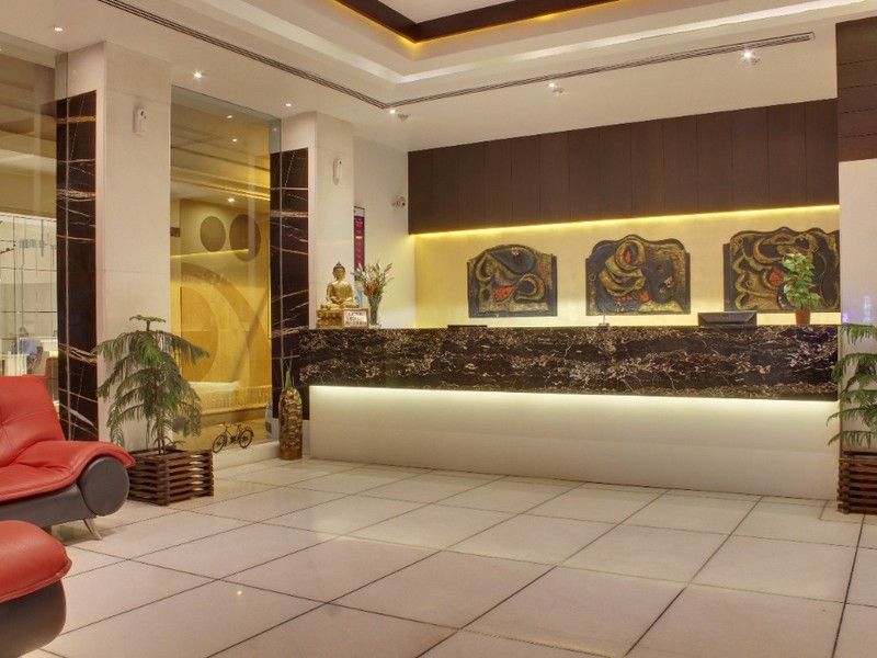 Hotel Godwin Deluxe modern designer reception lobby with sleek marble front desk, Buddha statue, and lounge seating in Central Delhi