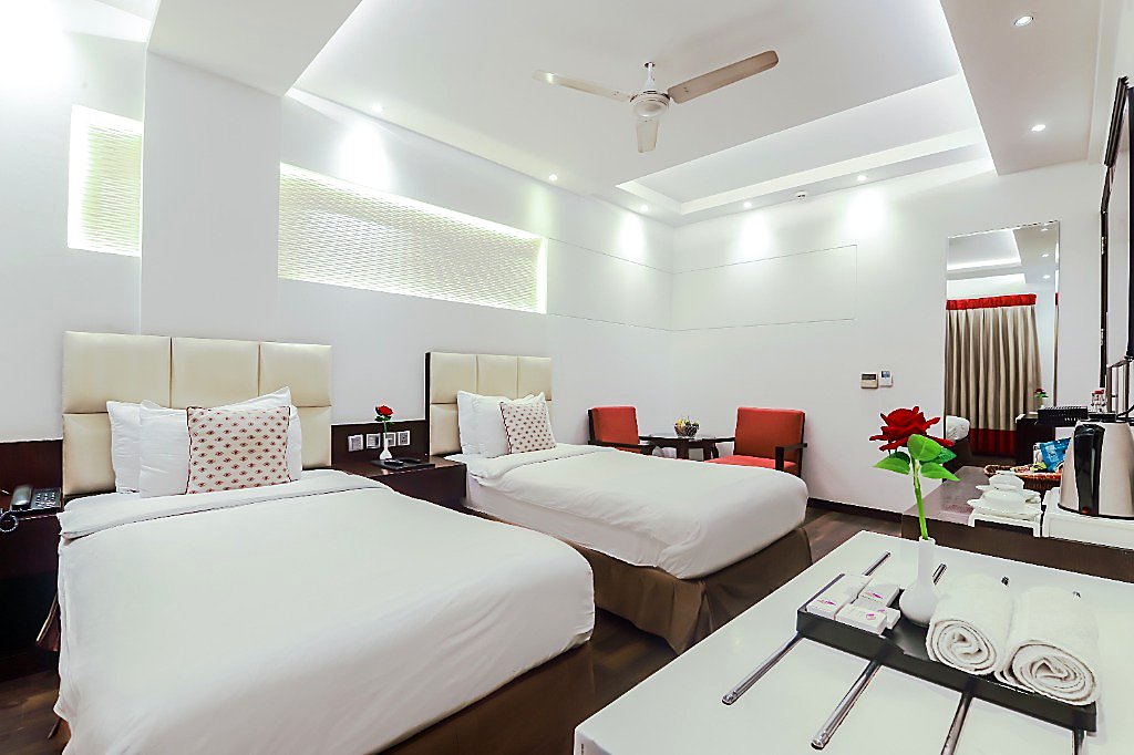 Executive Twin Room at Hotel Grand Godwin New Delhi — two separate plush single beds, reading lights, vanity counter, and central warmer