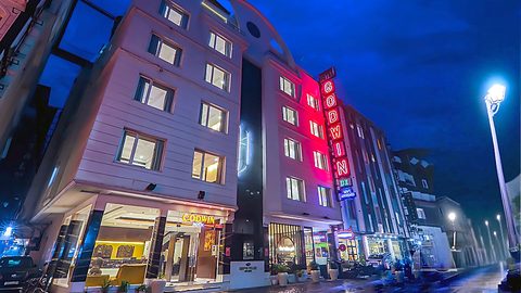 Hotel Godwin Deluxe exterior facade illuminated at night with neon sign, reception lobby, and The Indian Grill in Paharganj New Delhi