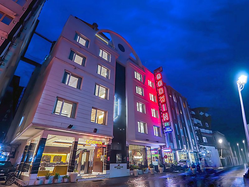 Hotel Godwin Deluxe building exterior facade illuminated at night with neon sign, reception lobby, and The Indian Grill in Paharganj New Delhi